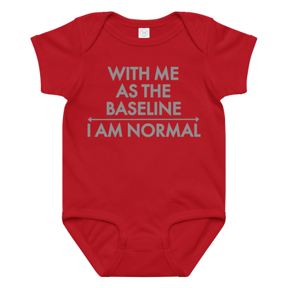 "With me as the baseline, I am normal" printed on a red baby jersey bodysuit laying on a flat surface amongst other clothes