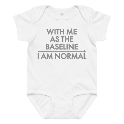 "With me as the baseline, I am normal" printed on a white baby jersey bodysuit laying on a flat surface amongst other clothes