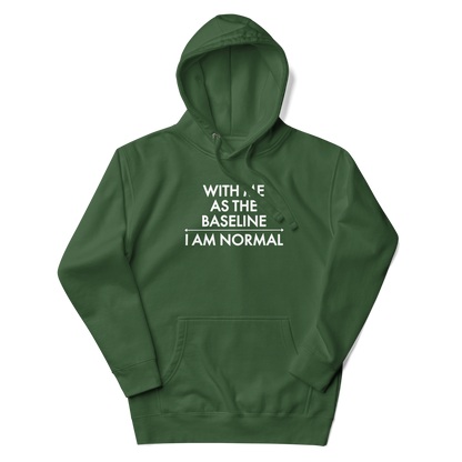 "With me as the baseline, I am normal" printed on a forest green unisex hoodie laying on a flat surface with the hood up