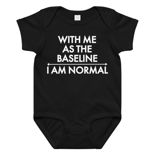 "With me as the baseline, I am normal" printed on a black baby jersey bodysuit laying on a flat surface amongst other clothes