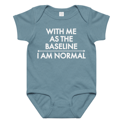 "With me as the baseline, I am normal" printed on a vintage indigo baby jersey bodysuit laying on a flat surface amongst other clothes