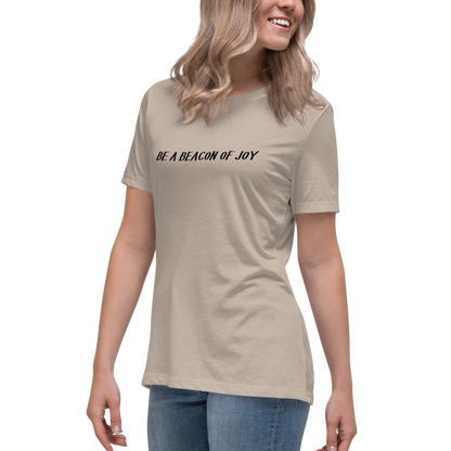 "Be a beacon of joy" printed on a heather stone women's relaxed t-shirt worn by a female
