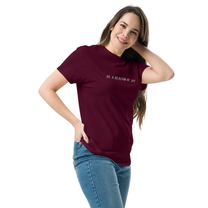"Be a beacon of joy" printed on a maroon unisex classic tee worn by a female