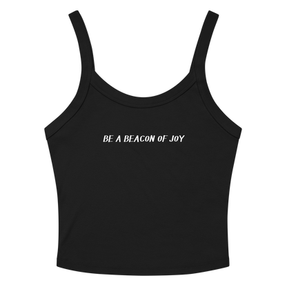 "Be a beacon of joy" printed on a solid black blend women's micro-rib tanktop laying on a flat surface amongst sunglasses and shorts