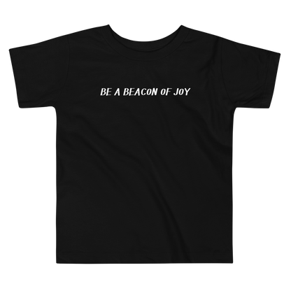"Be a beacon of joy" printed on a black toddler short sleeve tee laying on a flat surface