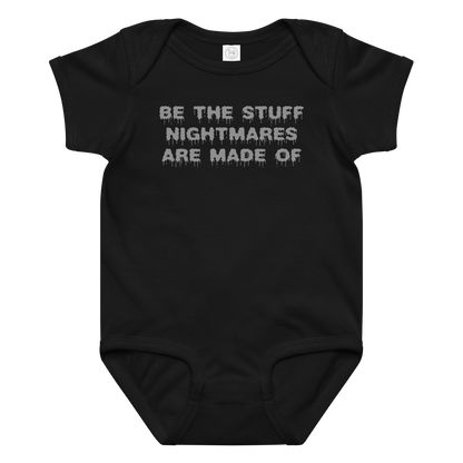 "Be the stuff nightmares are made of" printed on a black baby jersey bodysuit laying on a flat surface amongst other clothes