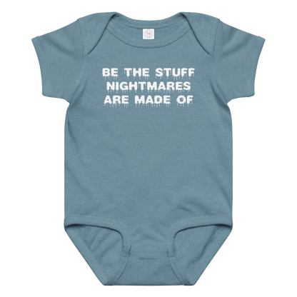 "Be the stuff nightmares are made of" printed on a vintage indigo baby jersey bodysuit laying on a flat surface amongst other clothes