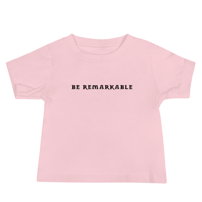 "Be remarkable" printed on a pink baby jersey short sleeve tee laying on a flat surface
