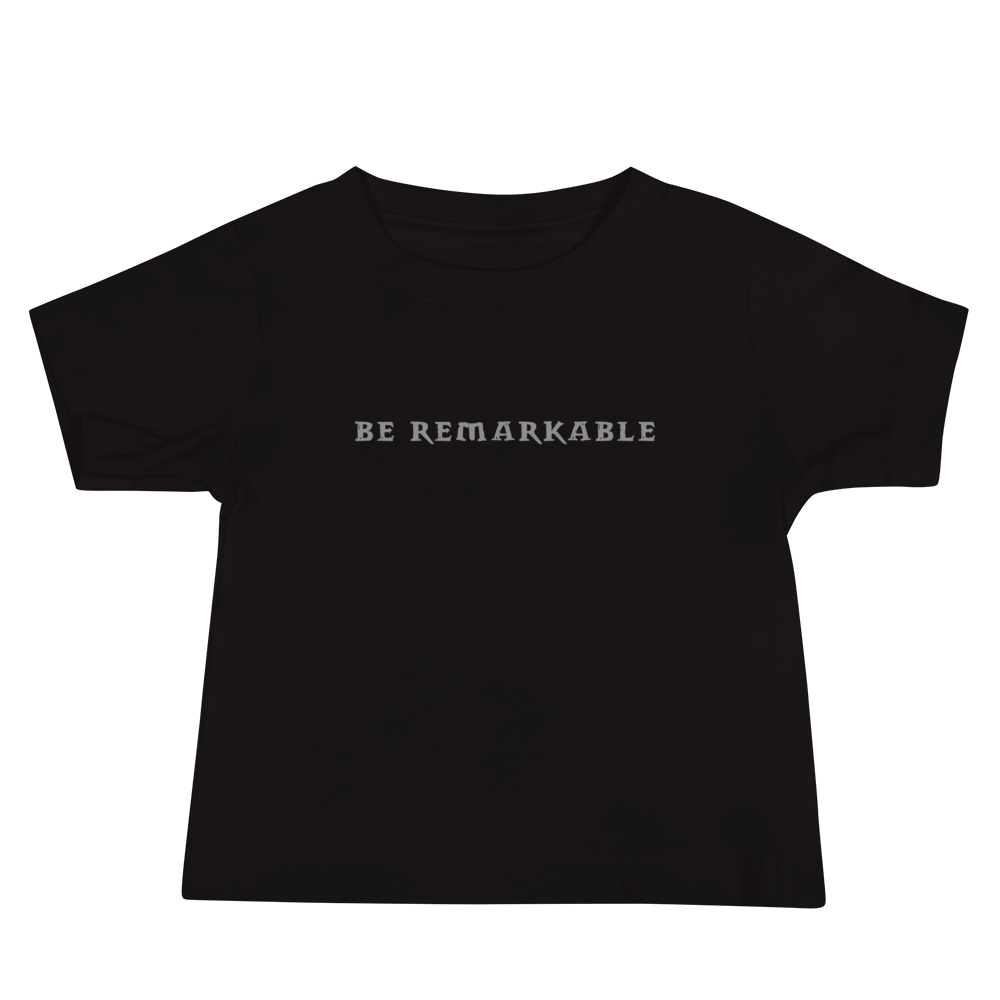 "Be remarkable" printed on a black baby jersey short sleeve tee laying on a flat surface