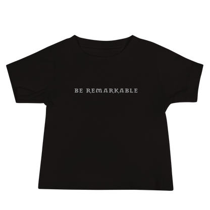 "Be remarkable" printed on a black baby jersey short sleeve tee laying on a flat surface