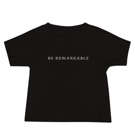 "Be remarkable" printed on a black baby jersey short sleeve tee laying on a flat surface
