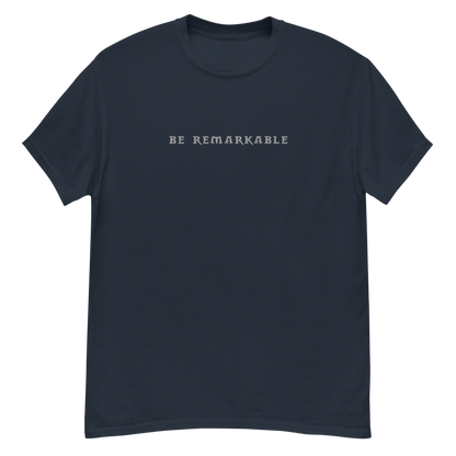 "Be remarkable" printed on a navy unisex classic tee laying on a flat surface
