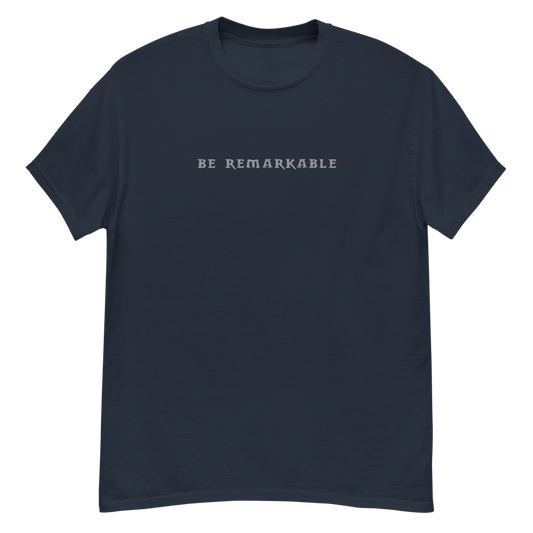 "Be remarkable" printed on a navy unisex classic tee laying on a flat surface