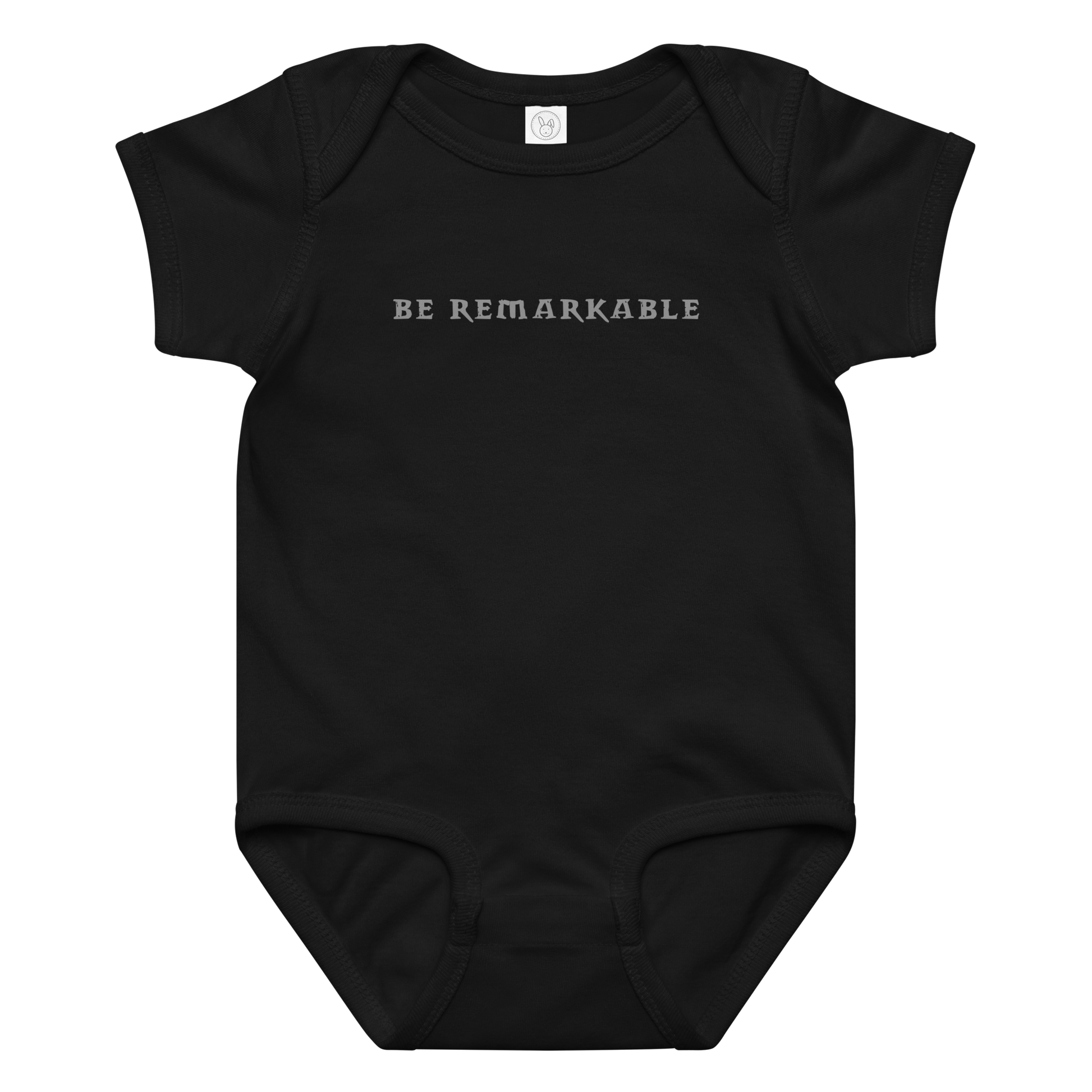 "Be remarkable" printed on a black baby jersey bodysuit laying on a flat surface amongst other clothes
