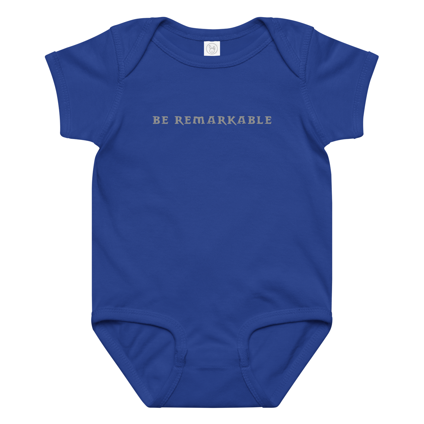 "Be remarkable" printed on a royal baby jersey bodysuit laying on a flat surface amongst other clothes