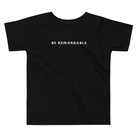 "Be remarkable" printed on a black toddler short sleeve tee laying on a flat surface