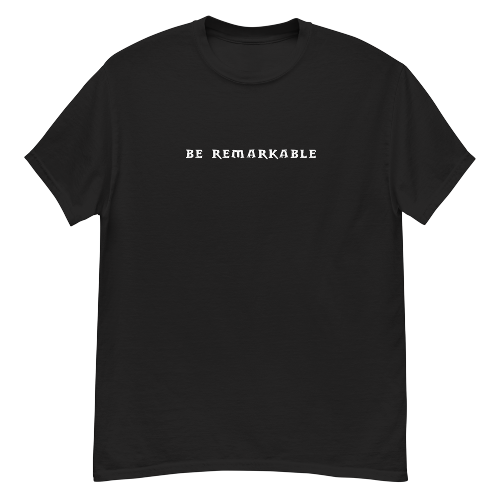"Be remarkable" printed on a black unisex classic tee laying on a flat surface