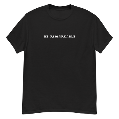 "Be remarkable" printed on a black unisex classic tee laying on a flat surface