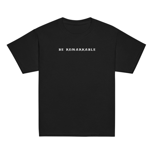 "Be remarkable" printed on a black youth classic tee laying on a flat surface