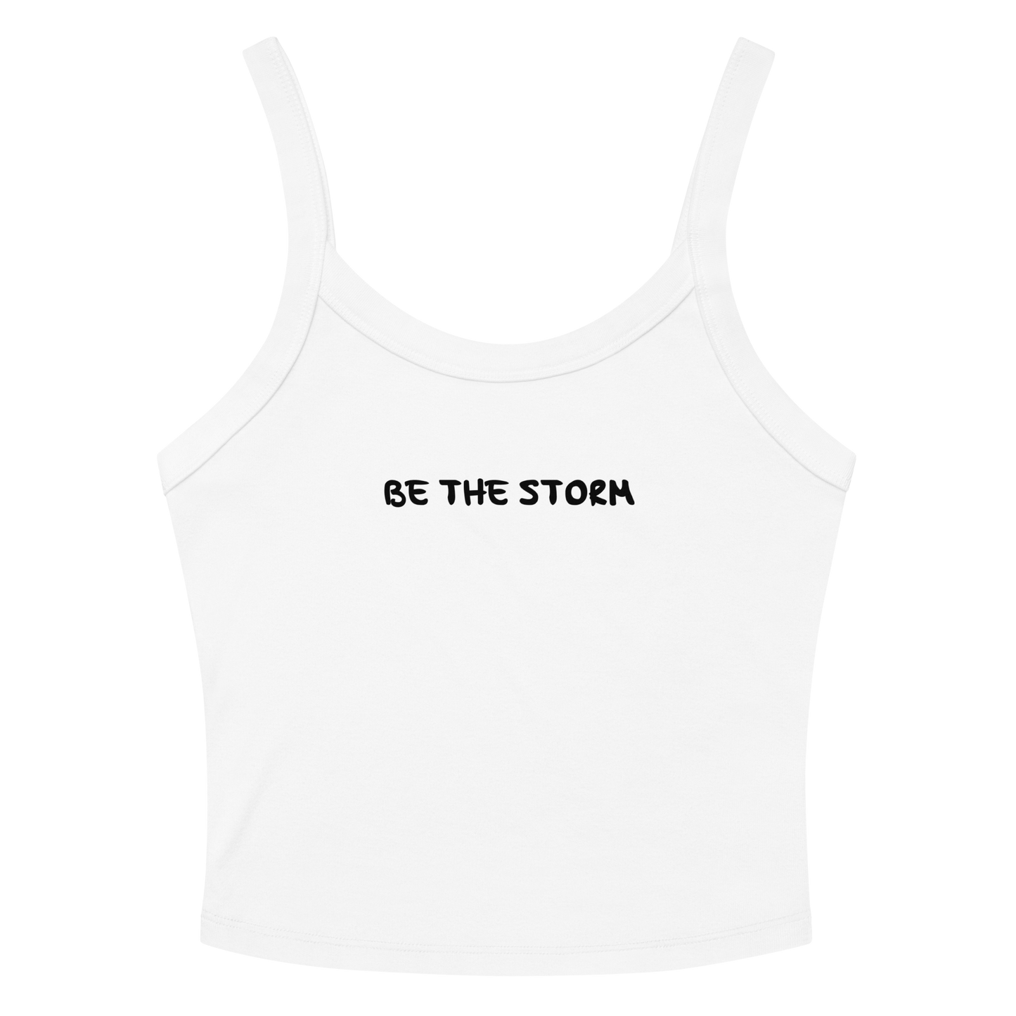 "Be the storm" printed on a solid white blend women's micro-rib tanktop laying on a flat surface amongst sunglasses and shorts
