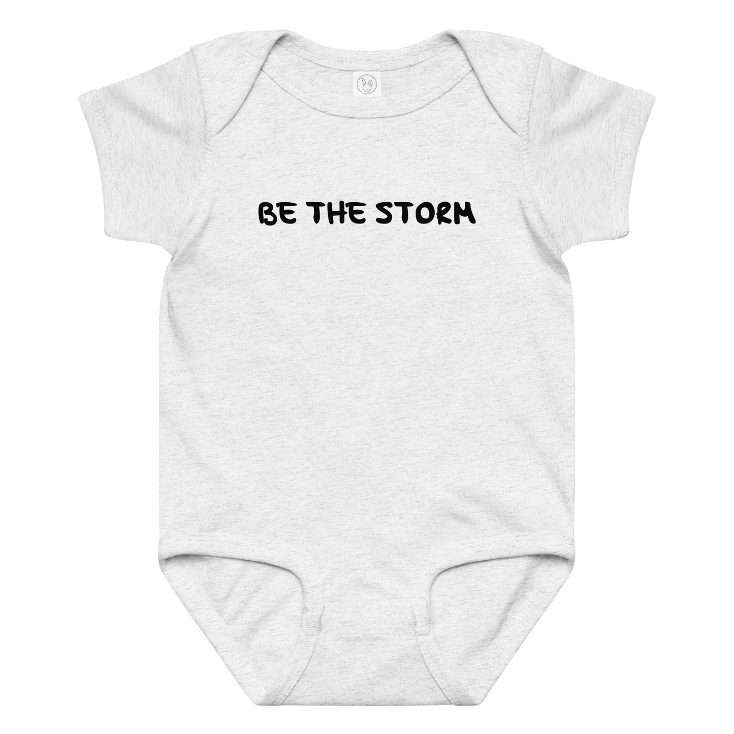 "Be the storm" printed on a ash baby jersey bodysuit laying on a flat surface amongst other clothes