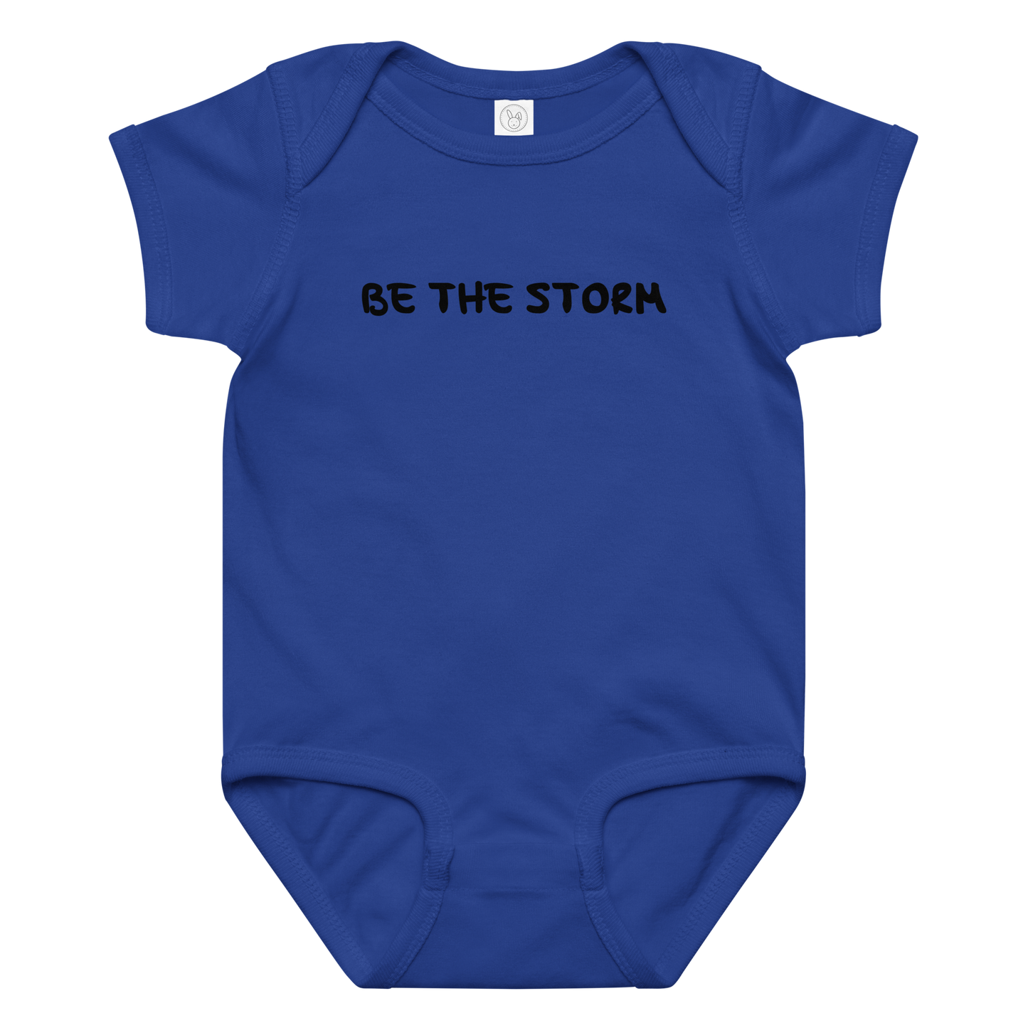 "Be the storm" printed on a royal baby jersey bodysuit laying on a flat surface amongst other clothes