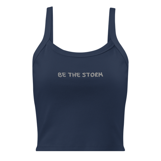 "Be the storm" printed on a solid navy blend women's micro-rib tanktop laying on a flat surface