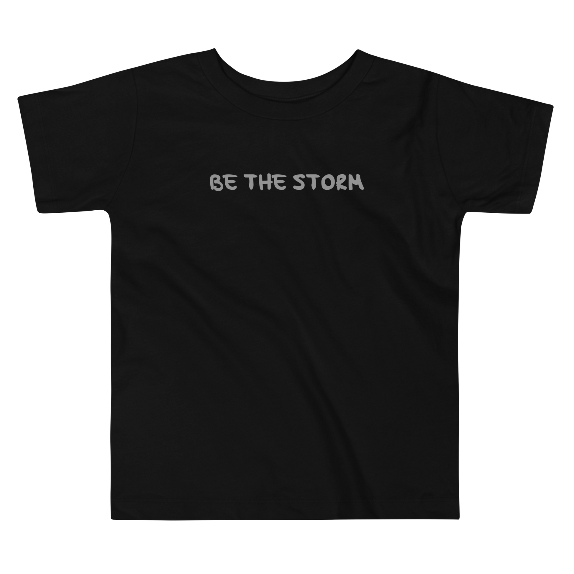 "Be the storm" printed on a black toddler short sleeve tee laying on a flat surface