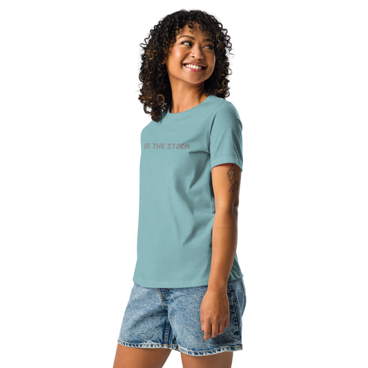 "Be the storm" printed on a heather blue lagoon women's relaxed t-shirt worn by a female