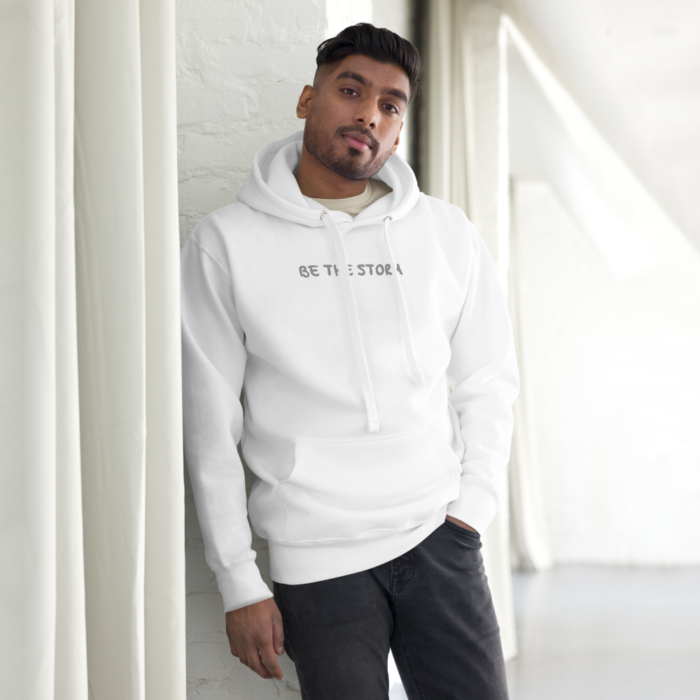 "Be the storm" printed on a white unisex hoodie worn by a male