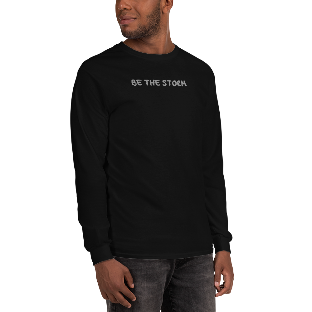 "Be the storm" printed on a black men's long sleeve shirt worn by a male