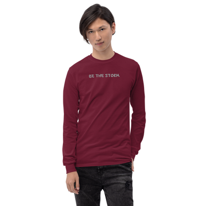 "Be the storm" printed on a maroon men's long sleeve shirt worn by a male