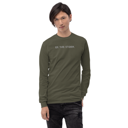 "Be the storm" printed on a military green men's long sleeve shirt worn by a male