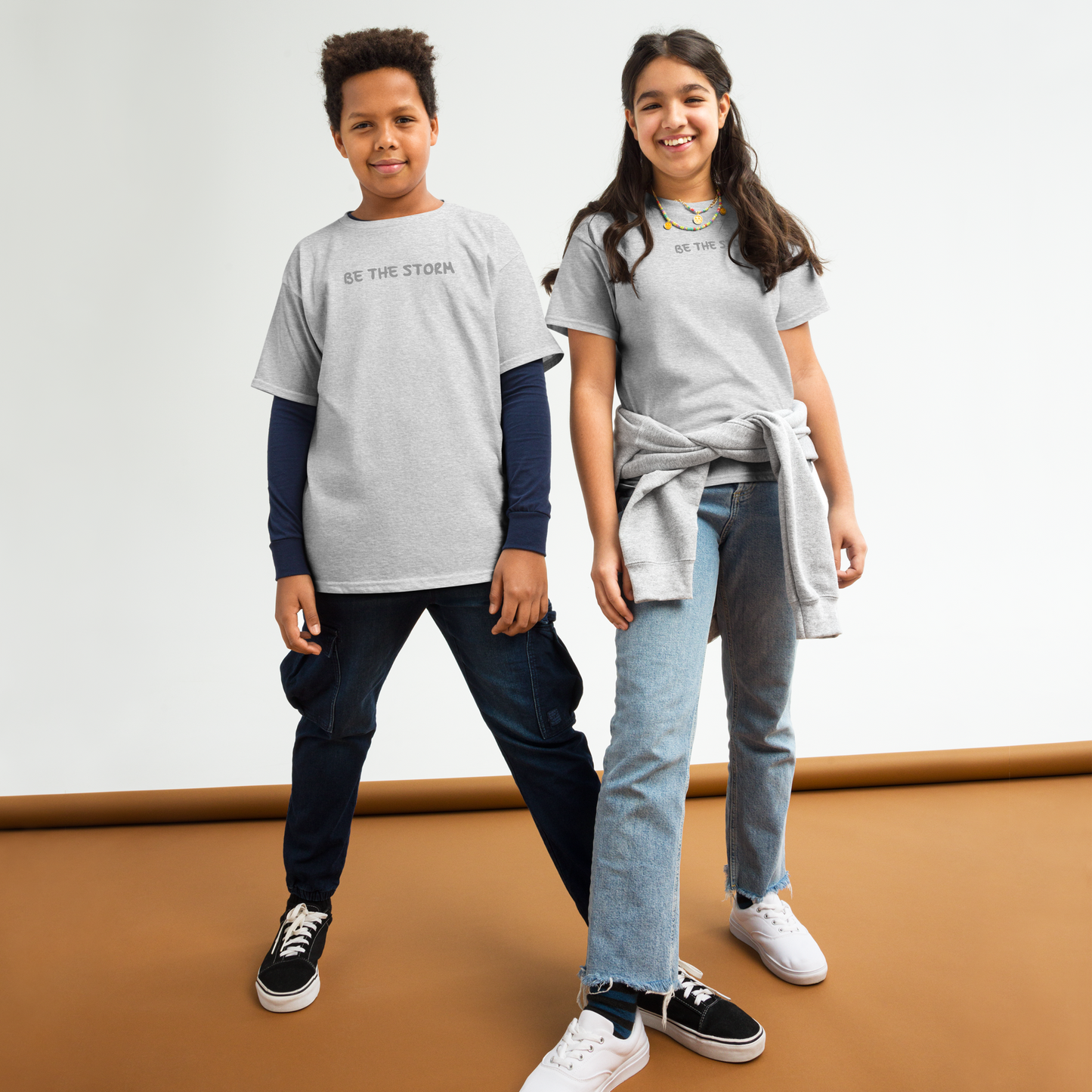"Be the storm" printed on a sport grey youth classic tee worn by a female and male