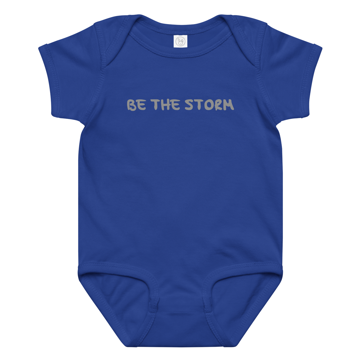 "Be the storm" printed on a royal baby jersey bodysuit laying on a flat surface amongst other clothes