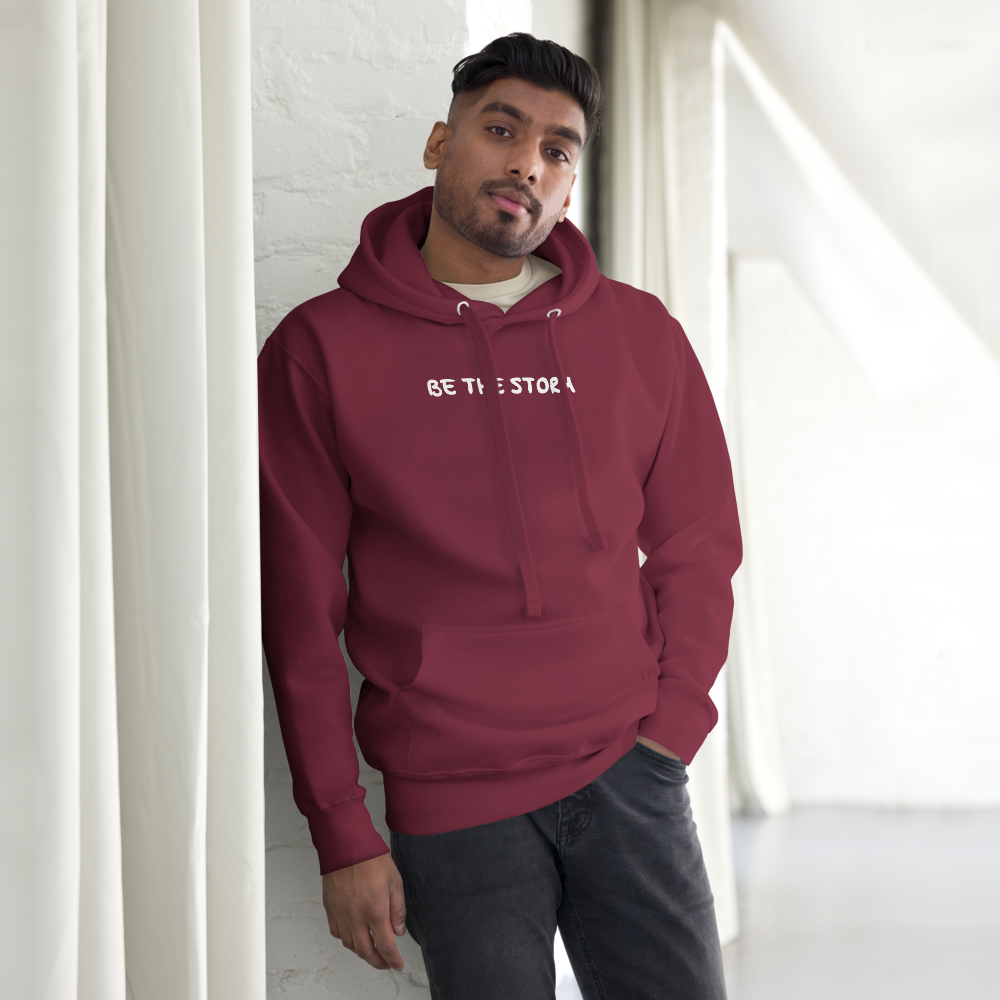 "Be the storm" printed on a maroon unisex hoodie worn by a male
