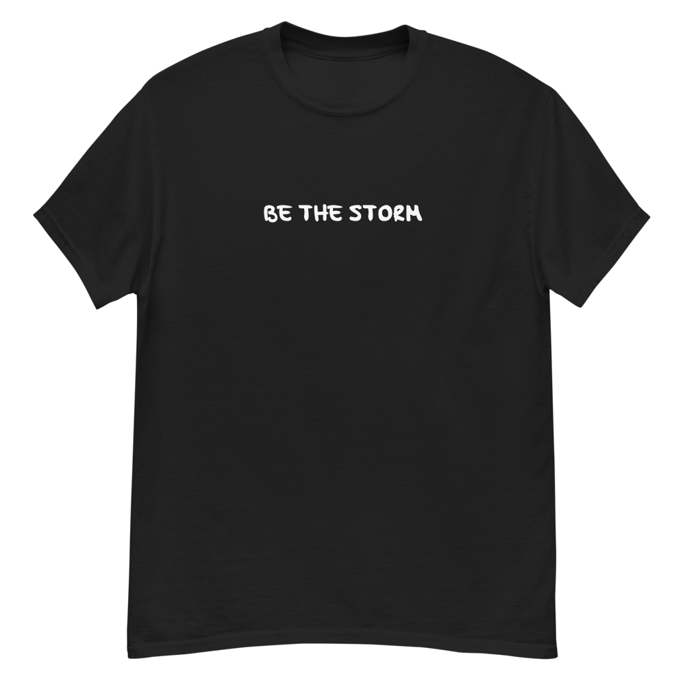 "Be the storm" printed on a black unisex classic tee laying on a flat surface
