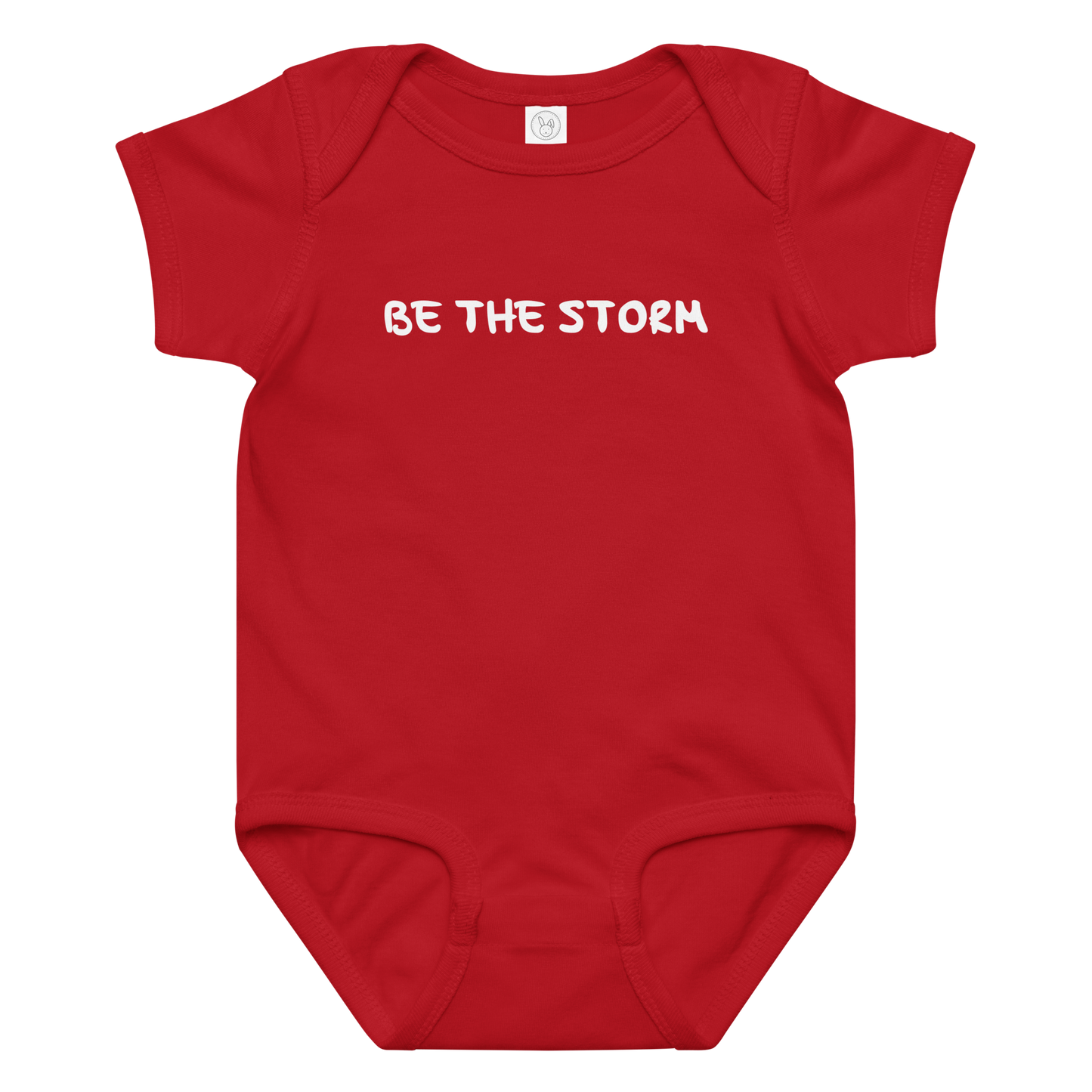"Be the storm" printed on a red baby jersey bodysuit laying on a flat surface amongst other clothes
