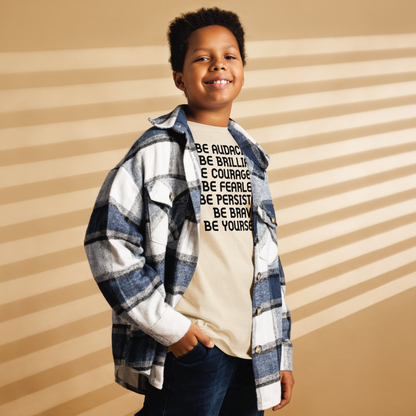 "Be Audacious Be Brilliant Be Courageous Be Fearless Be Persistent Be Brave Be Yourself!" printed on a natural youth classic tee worn by a male also wearing a jacket