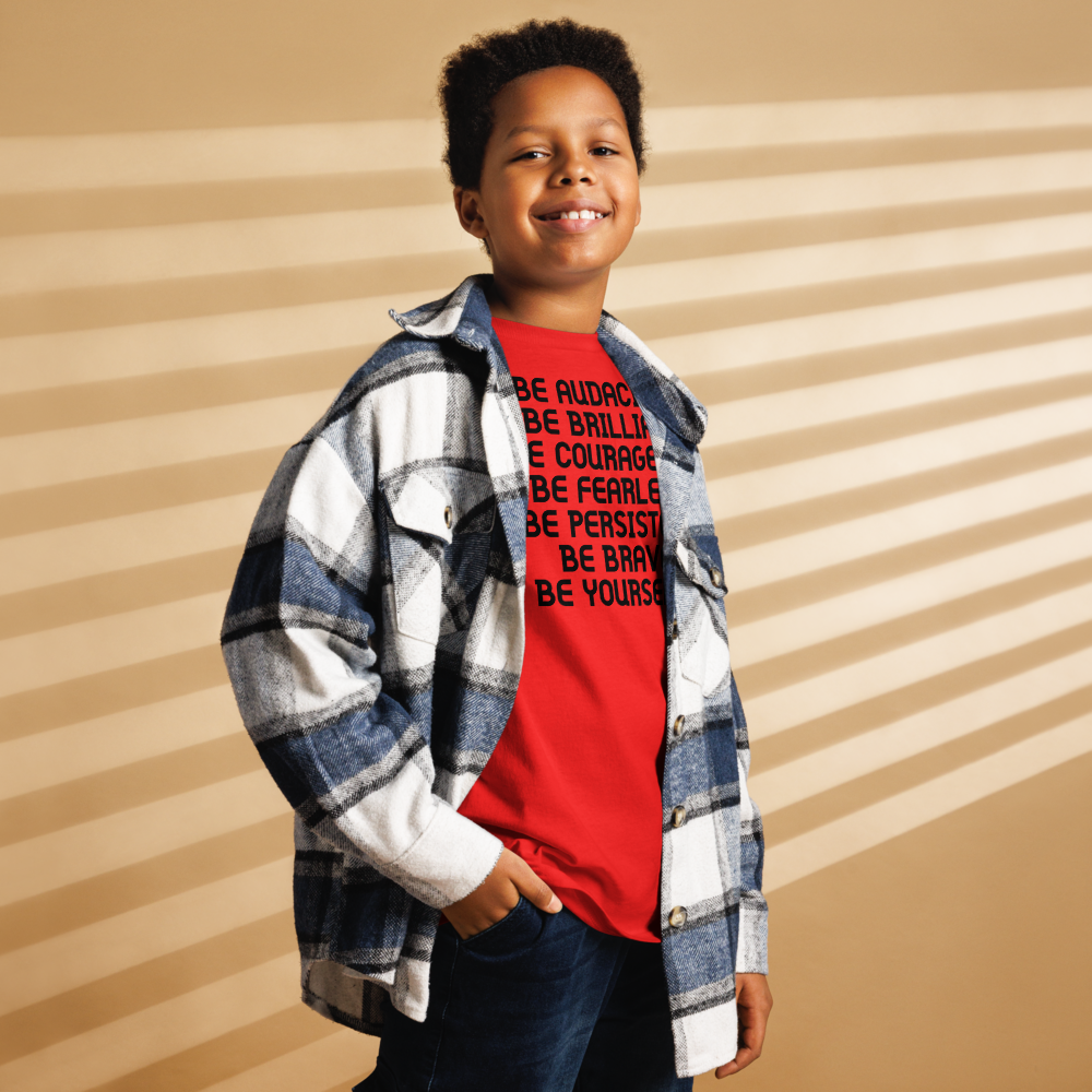 "Be Audacious Be Brilliant Be Courageous Be Fearless Be Persistent Be Brave Be Yourself!" printed on a red youth classic tee worn by a male also wearing a jacket