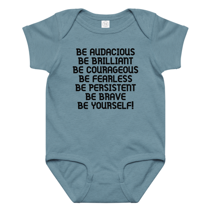 "Be Audacious Be Brilliant Be Courageous Be Fearless Be Persistent Be Brave Be Yourself!" printed on a vintage indigo baby jersey bodysuit laying on a flat surface amongst other clothes
