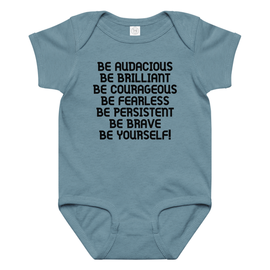 "Be Audacious Be Brilliant Be Courageous Be Fearless Be Persistent Be Brave Be Yourself!" printed on a vintage indigo baby jersey bodysuit laying on a flat surface amongst other clothes