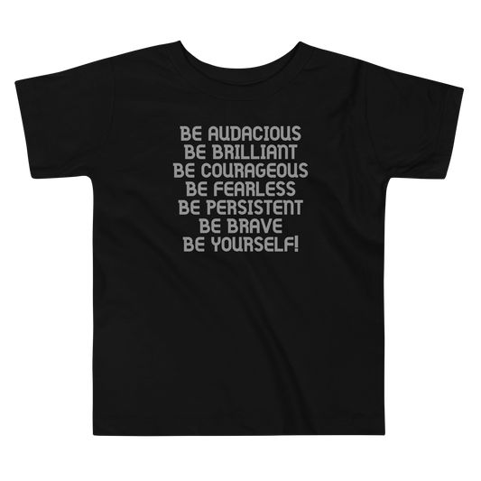 "Be Audacious Be Brilliant Be Courageous Be Fearless Be Persistent Be Brave Be Yourself!" printed on a black toddler short sleeve tee laying on a flat surface
