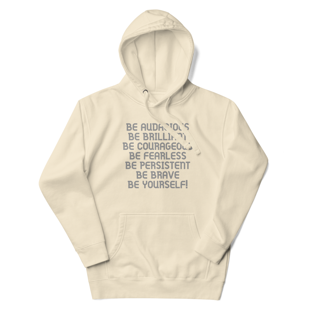 "Be Audacious Be Brilliant Be Courageous Be Fearless Be Persistent Be Brave Be Yourself!" printed on a bone unisex hoodie laying on a flat surface with the hood up