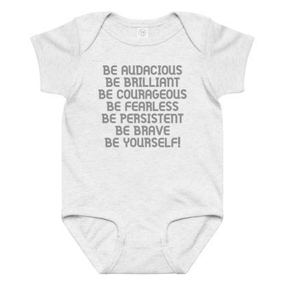 "Be Audacious Be Brilliant Be Courageous Be Fearless Be Persistent Be Brave Be Yourself!" printed on a ash baby jersey bodysuit laying on a flat surface amongst other clothes