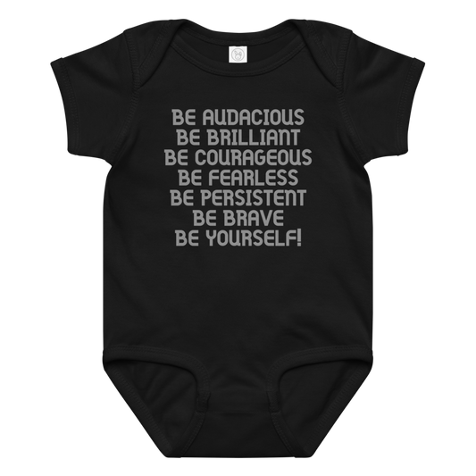"Be Audacious Be Brilliant Be Courageous Be Fearless Be Persistent Be Brave Be Yourself!" printed on a black baby jersey bodysuit laying on a flat surface amongst other clothes
