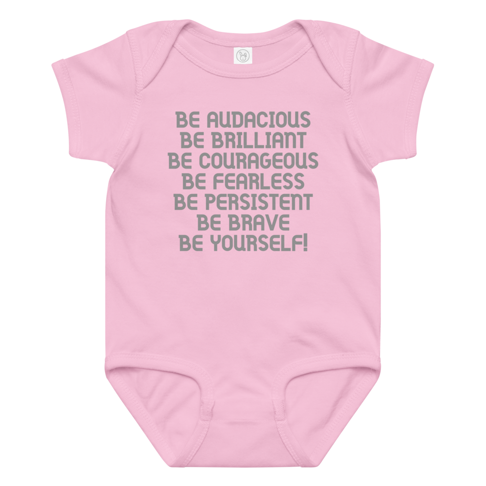 "Be Audacious Be Brilliant Be Courageous Be Fearless Be Persistent Be Brave Be Yourself!" printed on a pink baby jersey bodysuit laying on a flat surface amongst other clothes