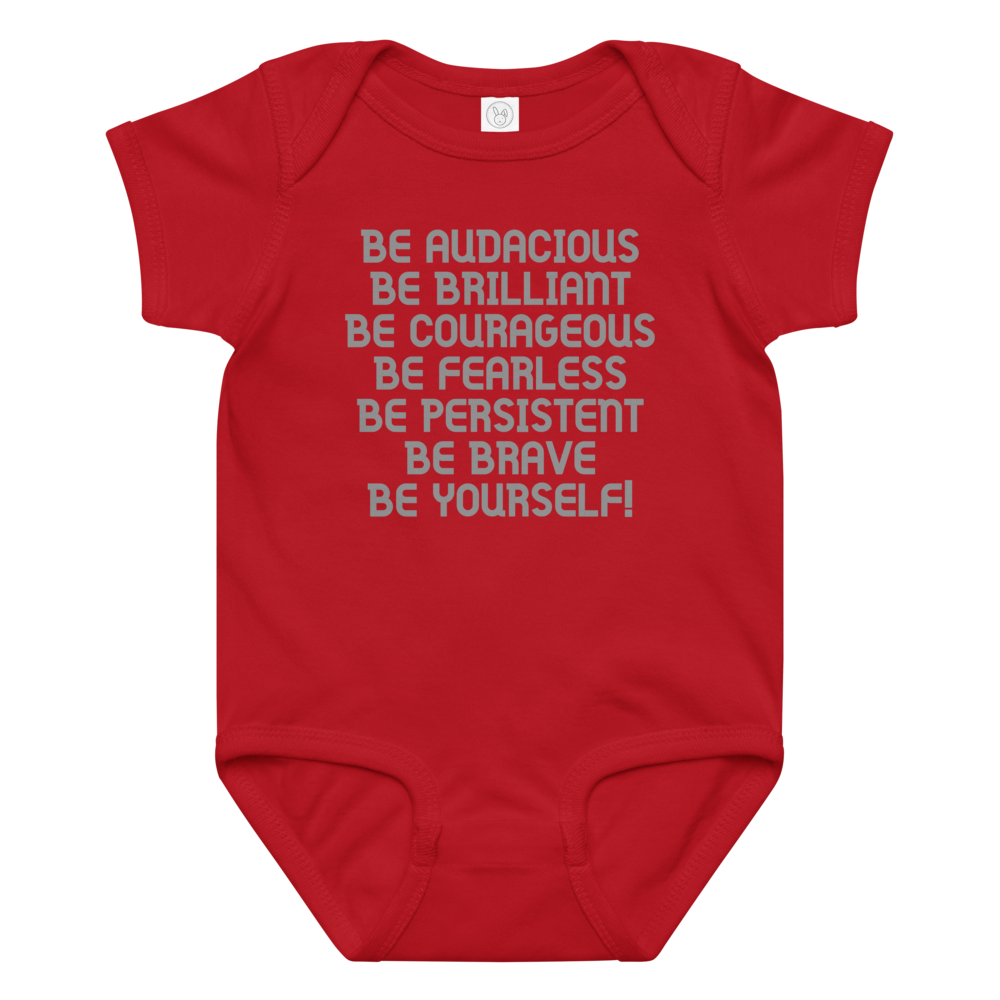 "Be Audacious Be Brilliant Be Courageous Be Fearless Be Persistent Be Brave Be Yourself!" printed on a red baby jersey bodysuit laying on a flat surface amongst other clothes