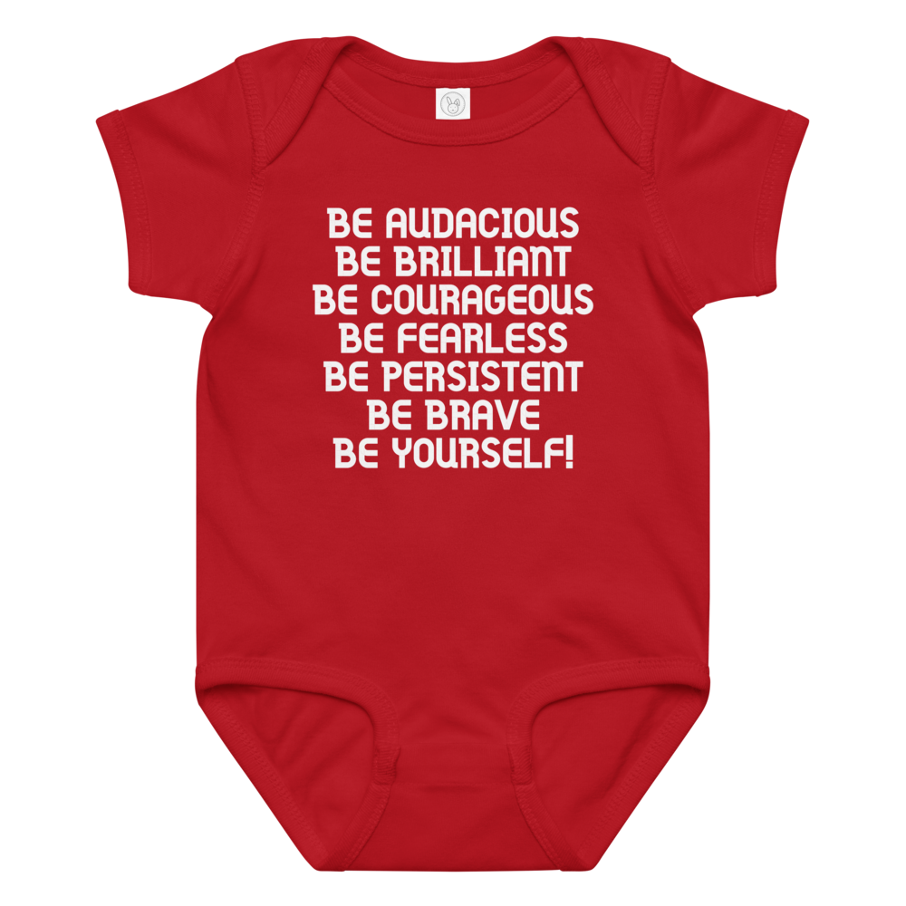 "Be Audacious Be Brilliant Be Courageous Be Fearless Be Persistent Be Brave Be Yourself!" printed on a red baby jersey bodysuit laying on a flat surface amongst other clothes