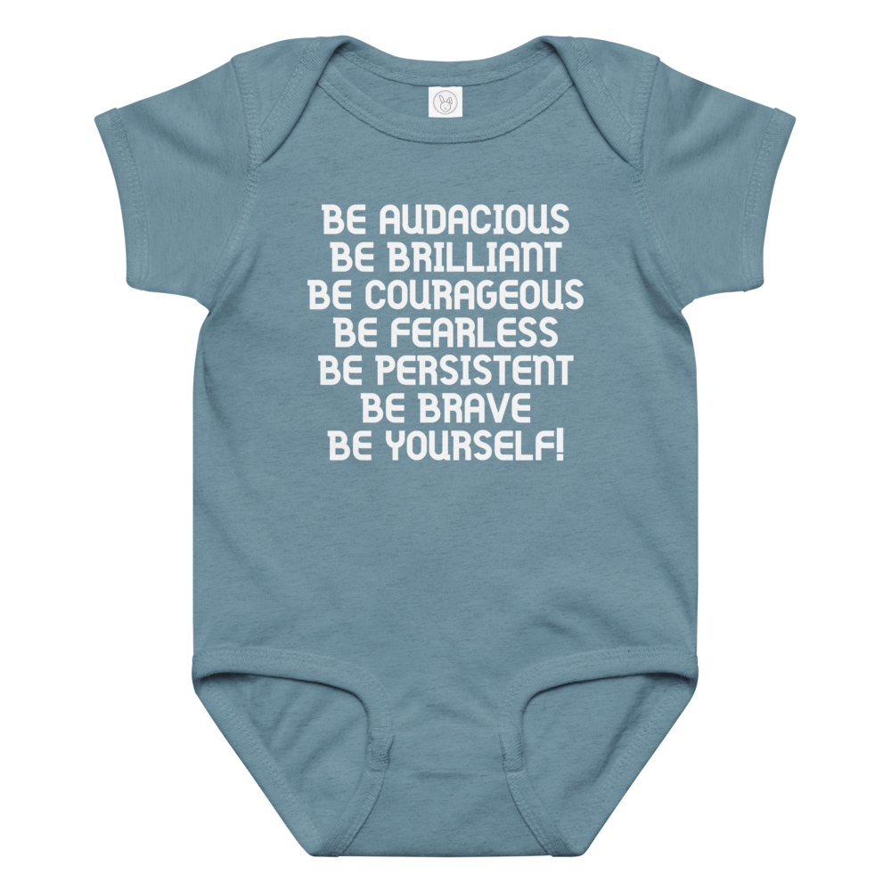 "Be Audacious Be Brilliant Be Courageous Be Fearless Be Persistent Be Brave Be Yourself!" printed on a vintage indigo baby jersey bodysuit laying on a flat surface amongst other clothes